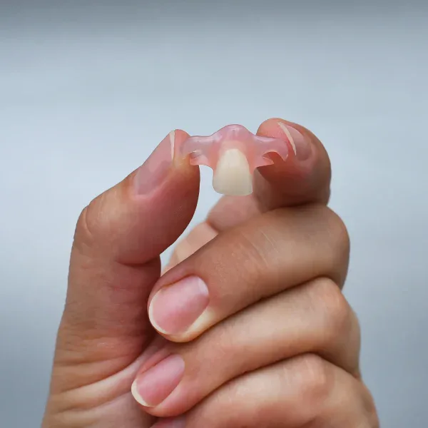 Prótesis dental flexible parcial sostenida entre los dedos